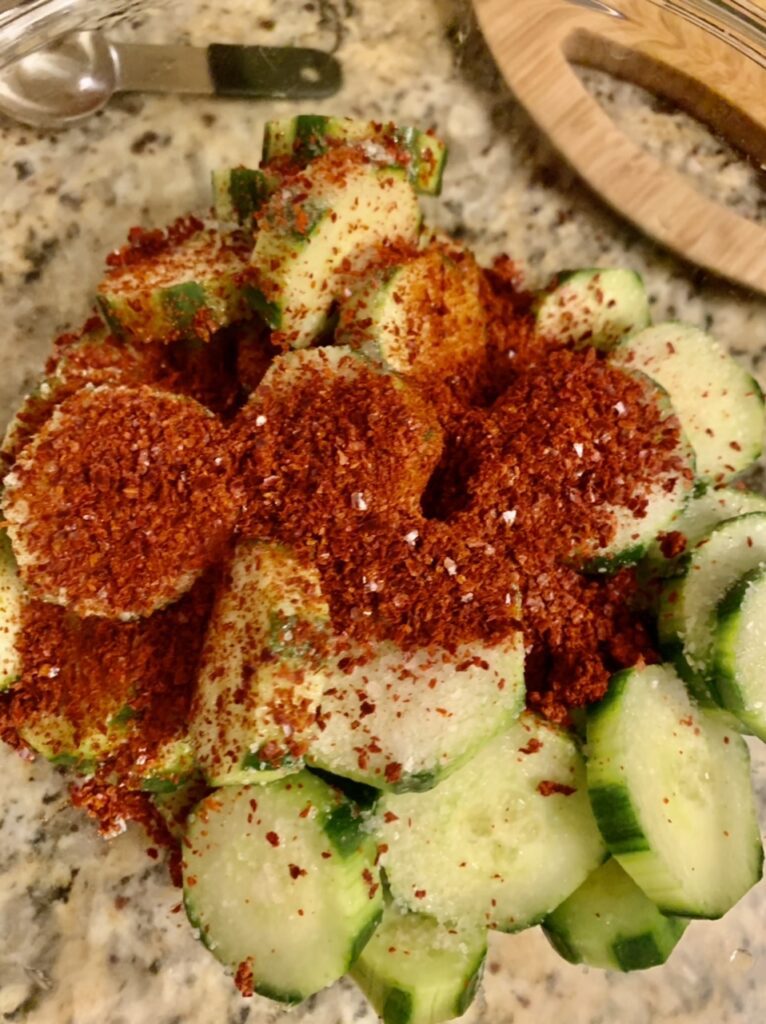 Adding gochugaru, salt and sugar to cucumber slices to make Spicy Korean Marinated Cucumber Oi Muchim